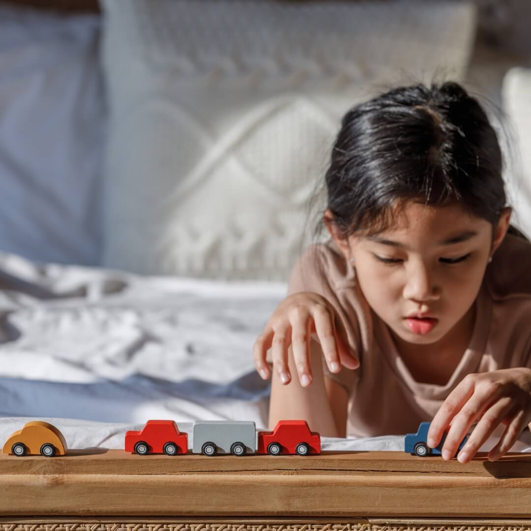 Child playing with toy cars on a wooden surface